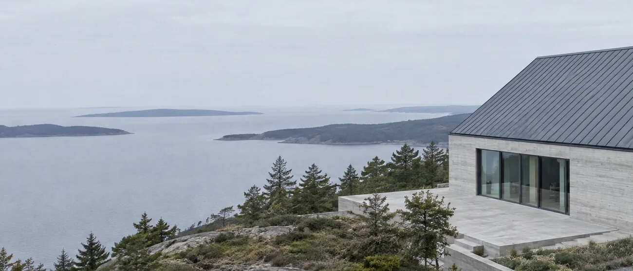 Grey sea and low islands beyond pine trees, the corner of the house at the right edge.